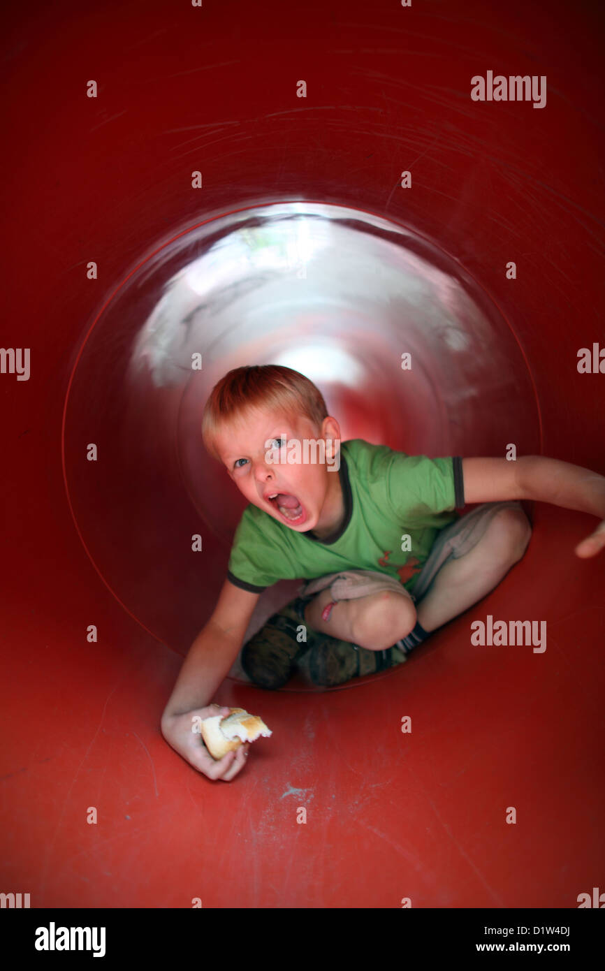Berlino, Germania, ragazzo esegue la scansione attraverso un tunnel su un parco giochi Foto Stock