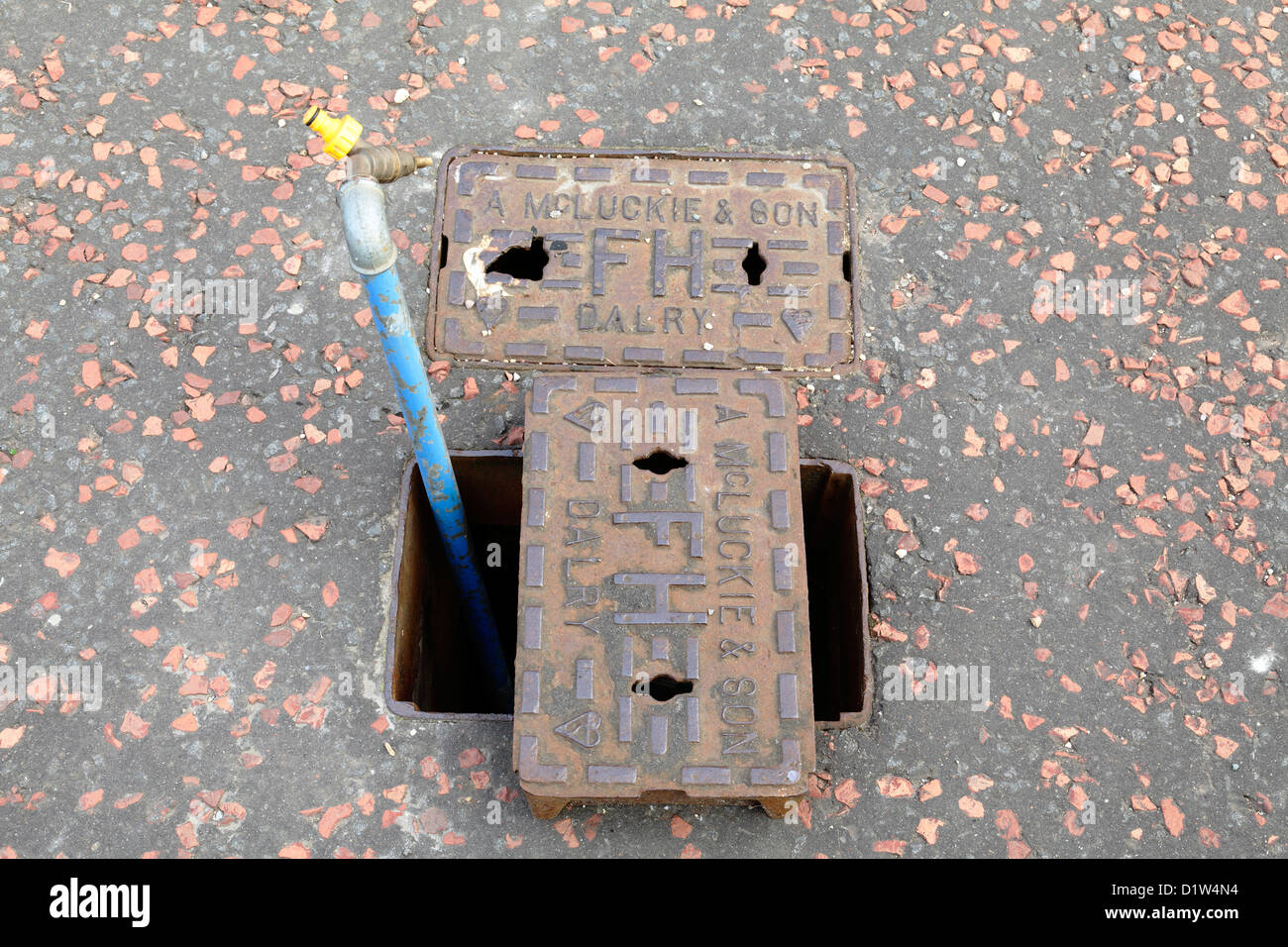 Tubo di alimentazione dell'acqua temporaneo installato su un pavimento in una scatola di superficie idrante di ghisa prodotta da una McLuckie, Glasgow, Scozia, Regno Unito Foto Stock