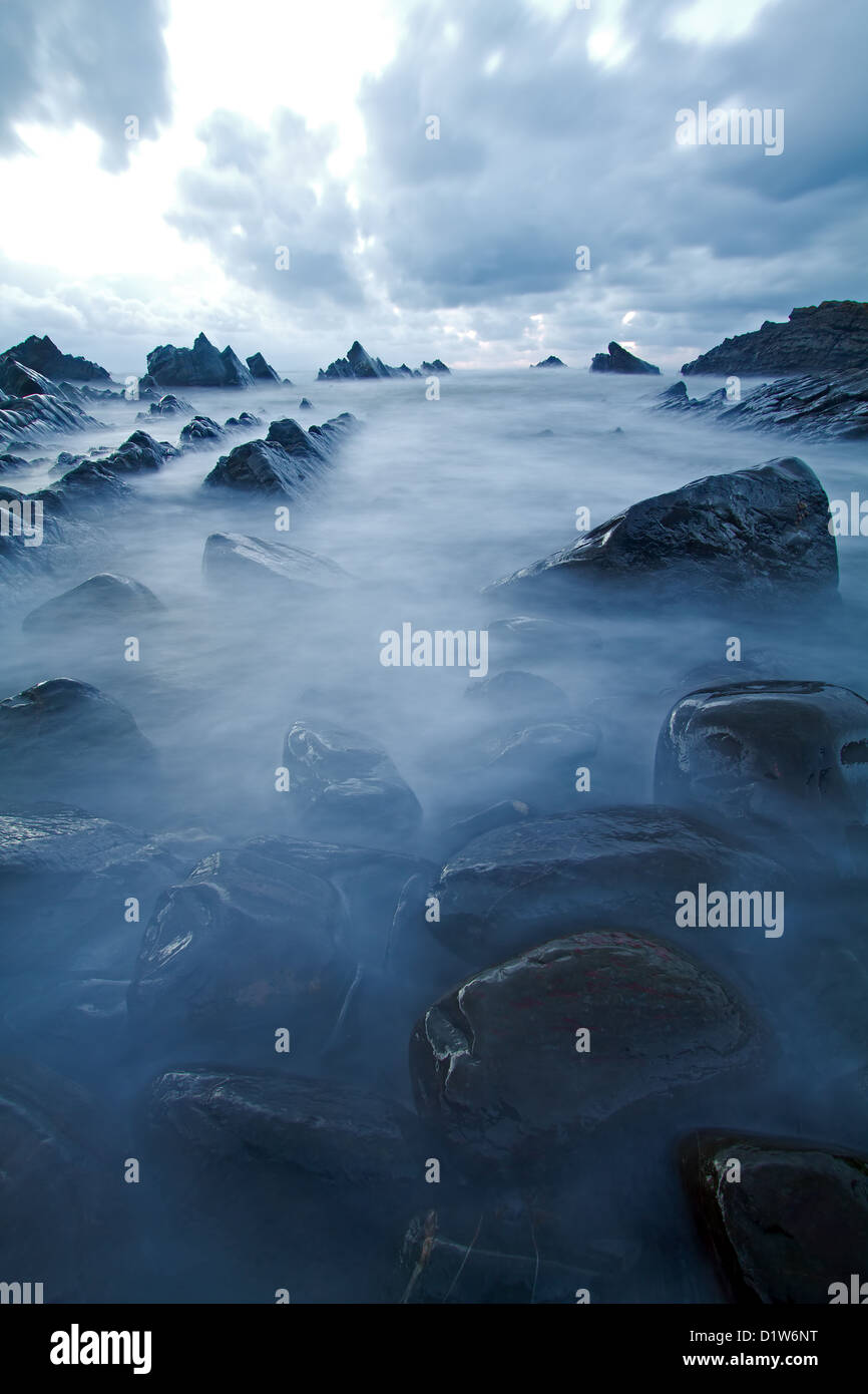 Rocce frastagliate si aggettano dall'acqua a Hartland Quay, Devon Foto Stock