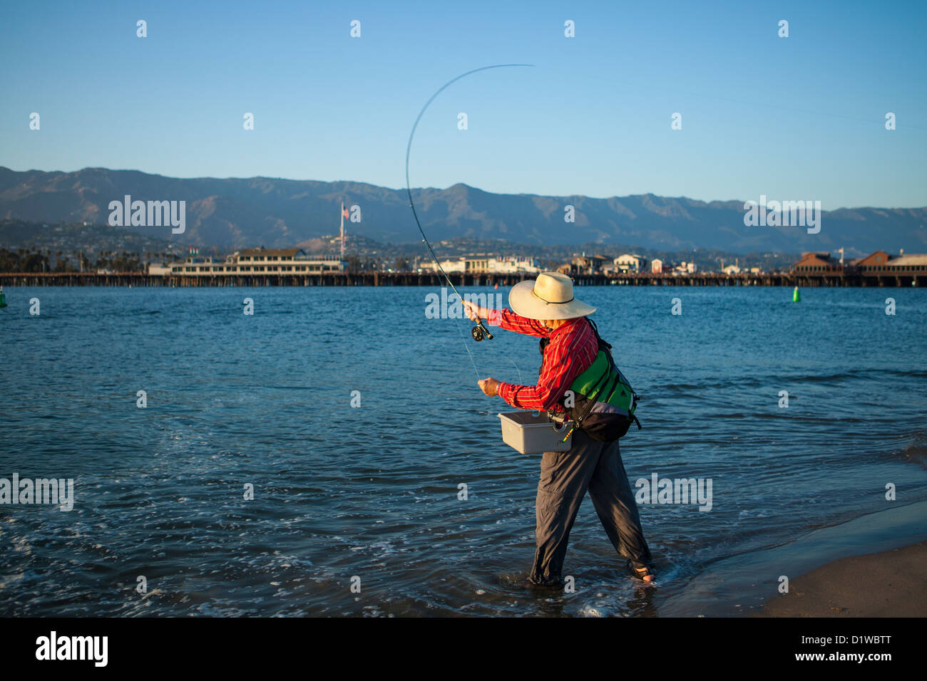 Saltwater flyfisherman casting per surf pesce persico con la banchina in background, porto sandbar, Santa Barbara, California Foto Stock