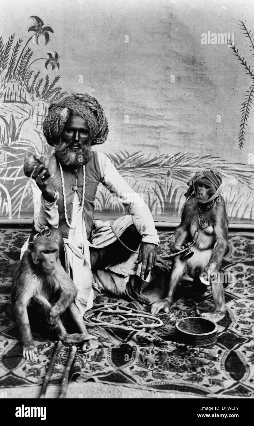 India - Fakir con scimmie Fakir indiano, ritratto a figura intera, seduto su tela con due scimmie. Circa 1900 Foto Stock