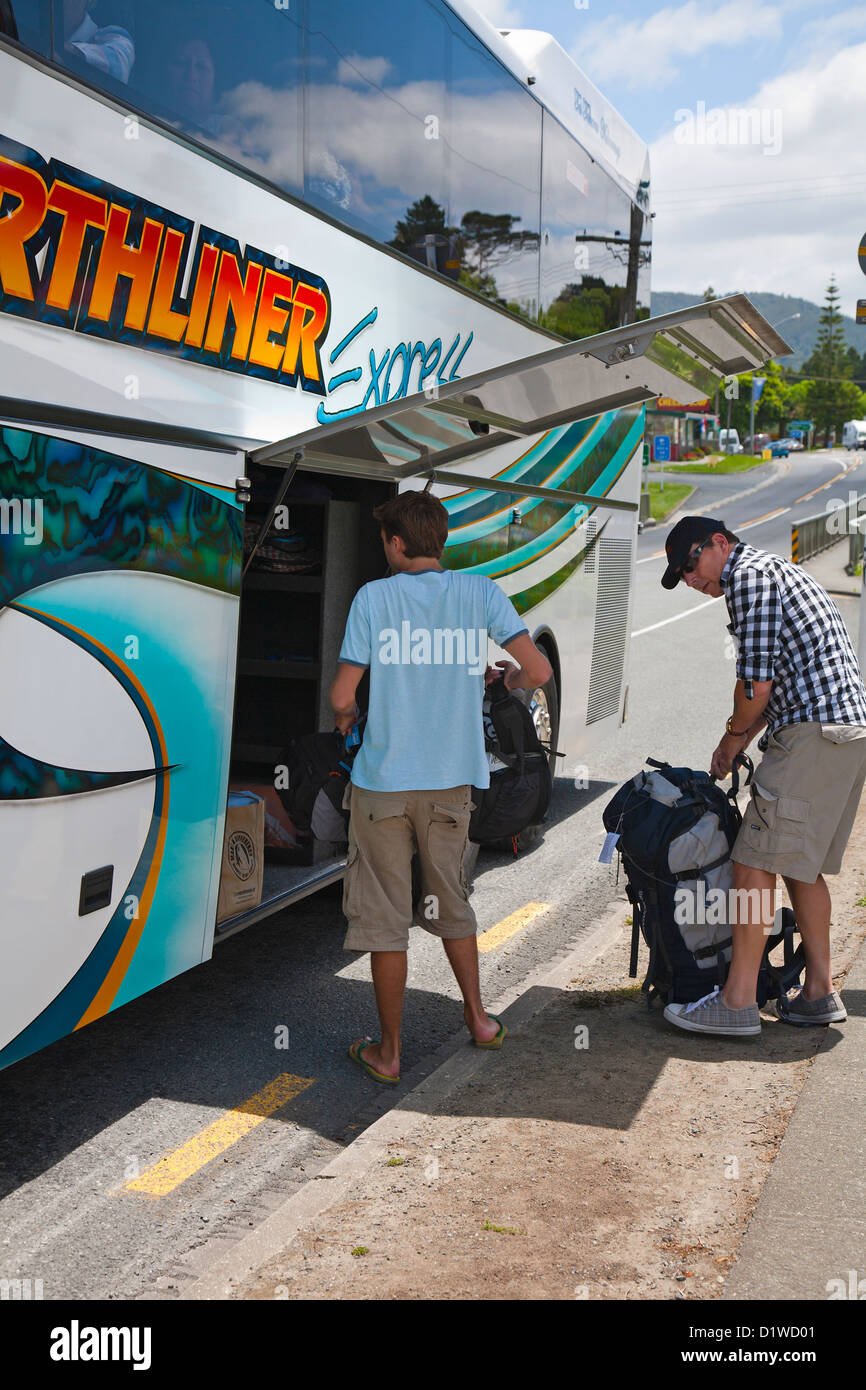 Due backpackers il caricamento nei loro zaini su un pullman. Northland e North Island, Nuova Zelanda. Foto Stock