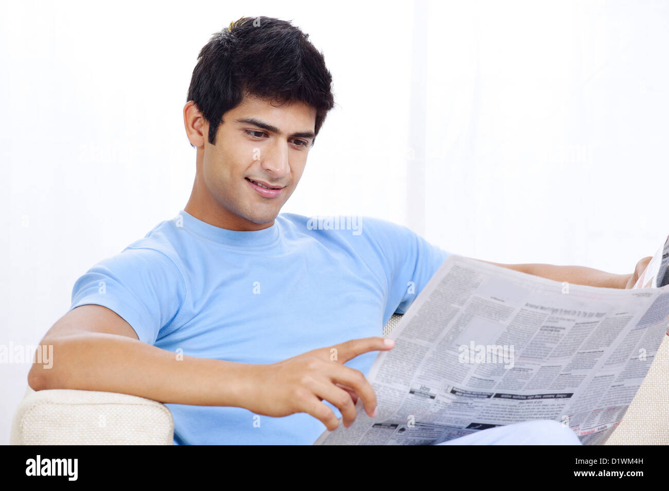 Giovane uomo indiano quotidiano di lettura Foto Stock