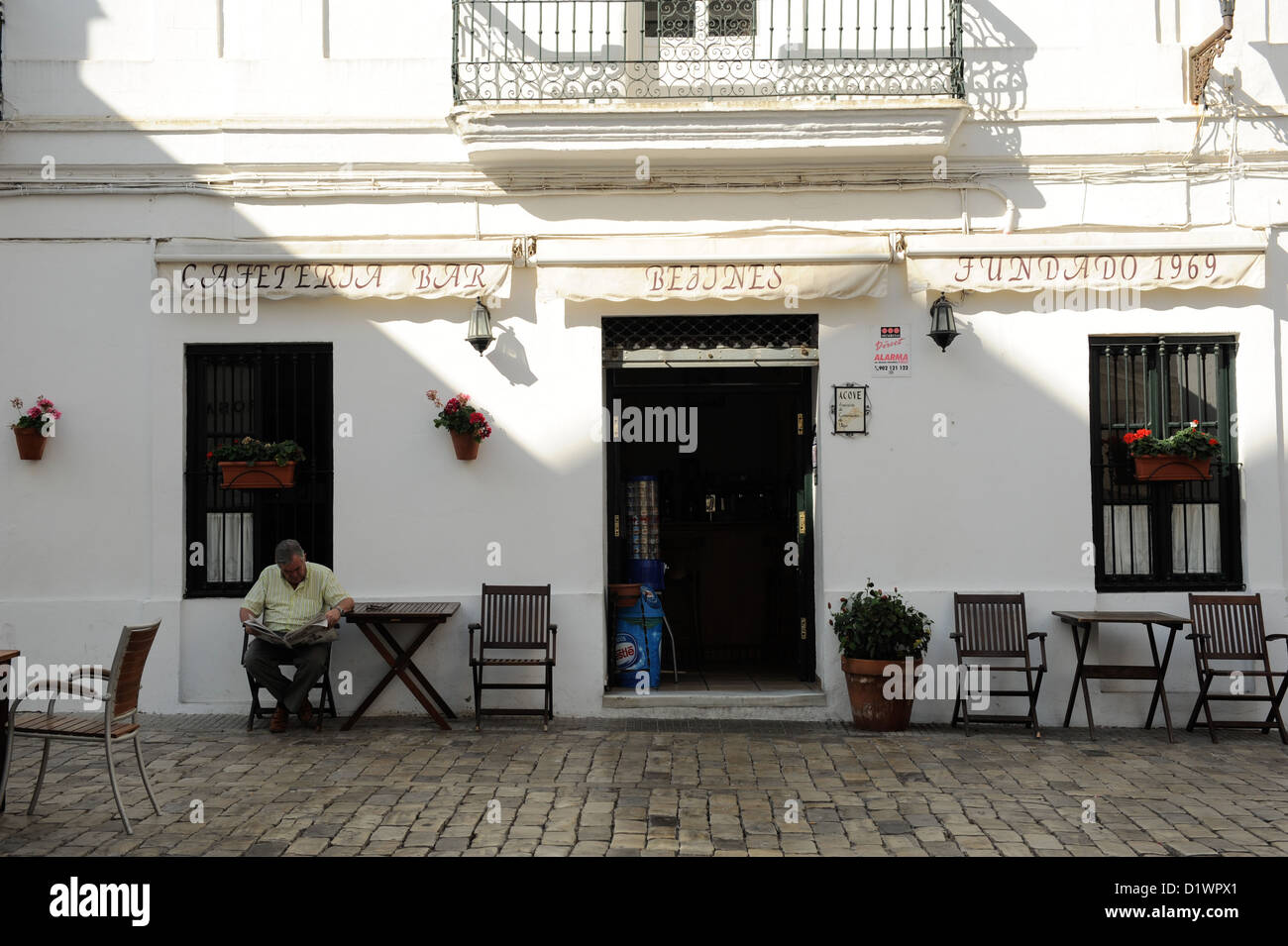 L'uomo la lettura davanti al bar a Vejer de la Frontera, uno dei Pueblos Blancos o bianche città dell'Andalusia, Spagna Foto Stock
