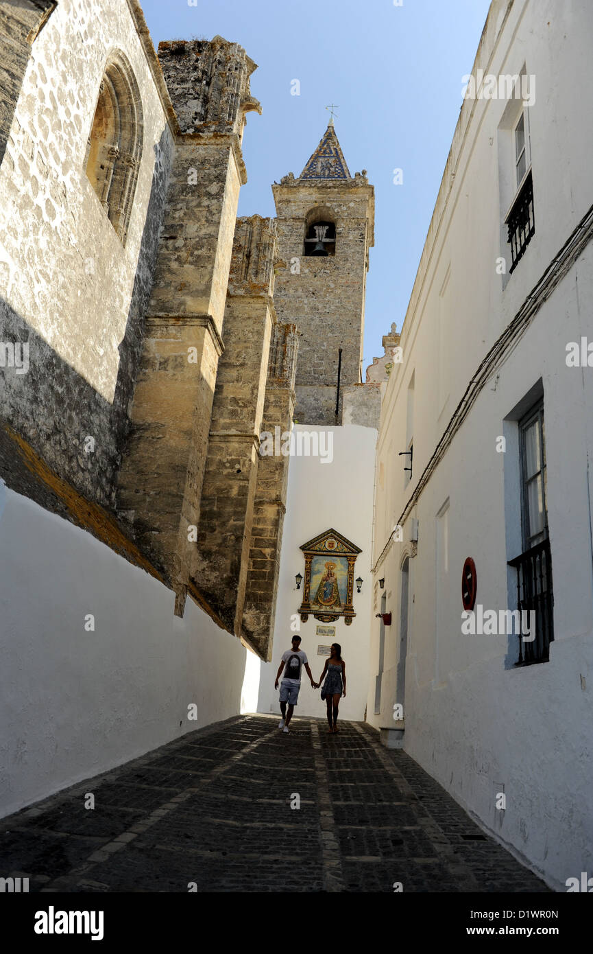 Un paio di camminare mano nella mano a fianco del Divino la chiesa del Salvador, Vejer de la Frontera, Andalusia, Spagna Foto Stock