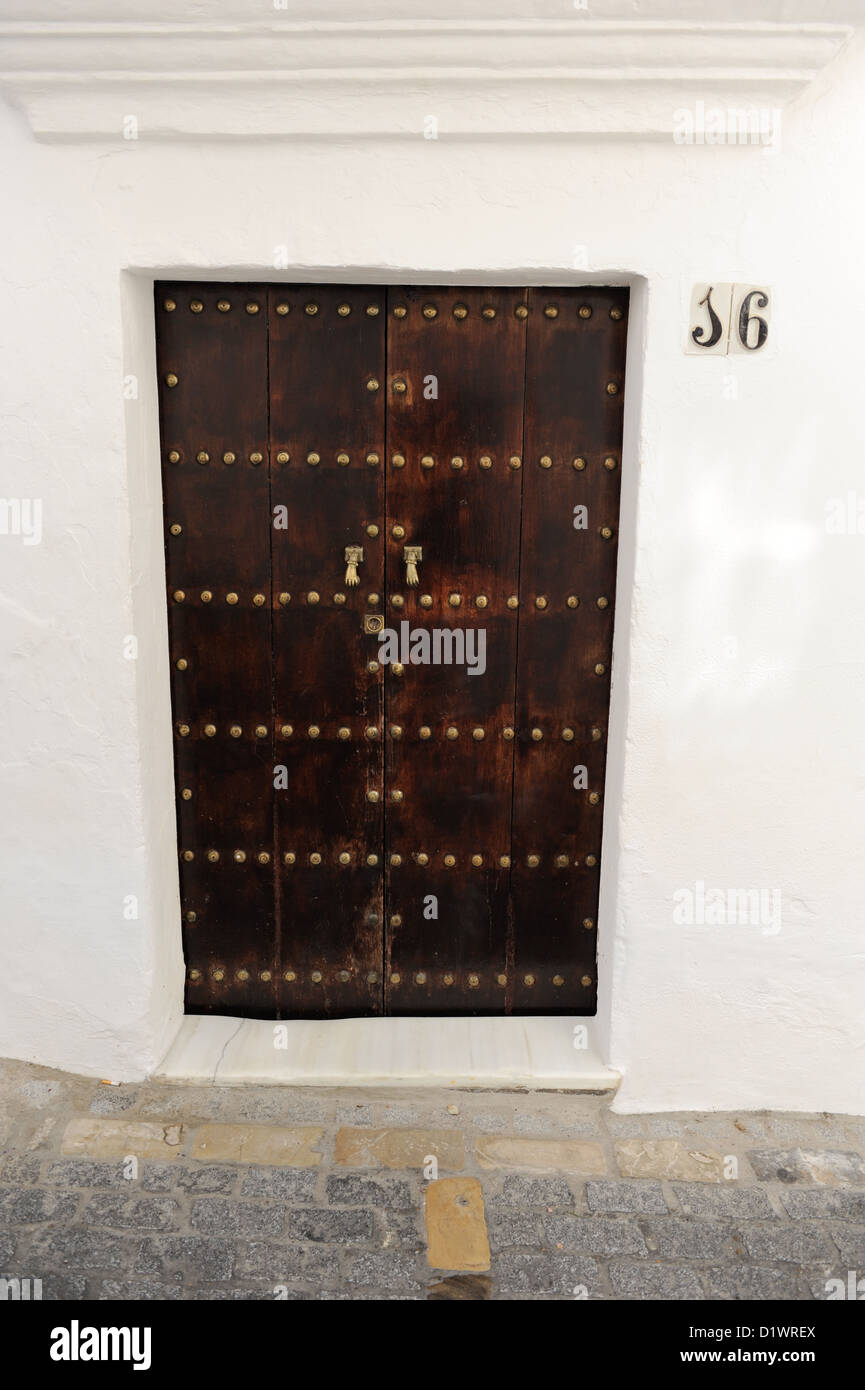 Vecchio brown porta di legno, Numero 16, Vejer de la Frontera, uno dei Pueblos Blancos o bianche città dell'Andalusia, Spagna Foto Stock
