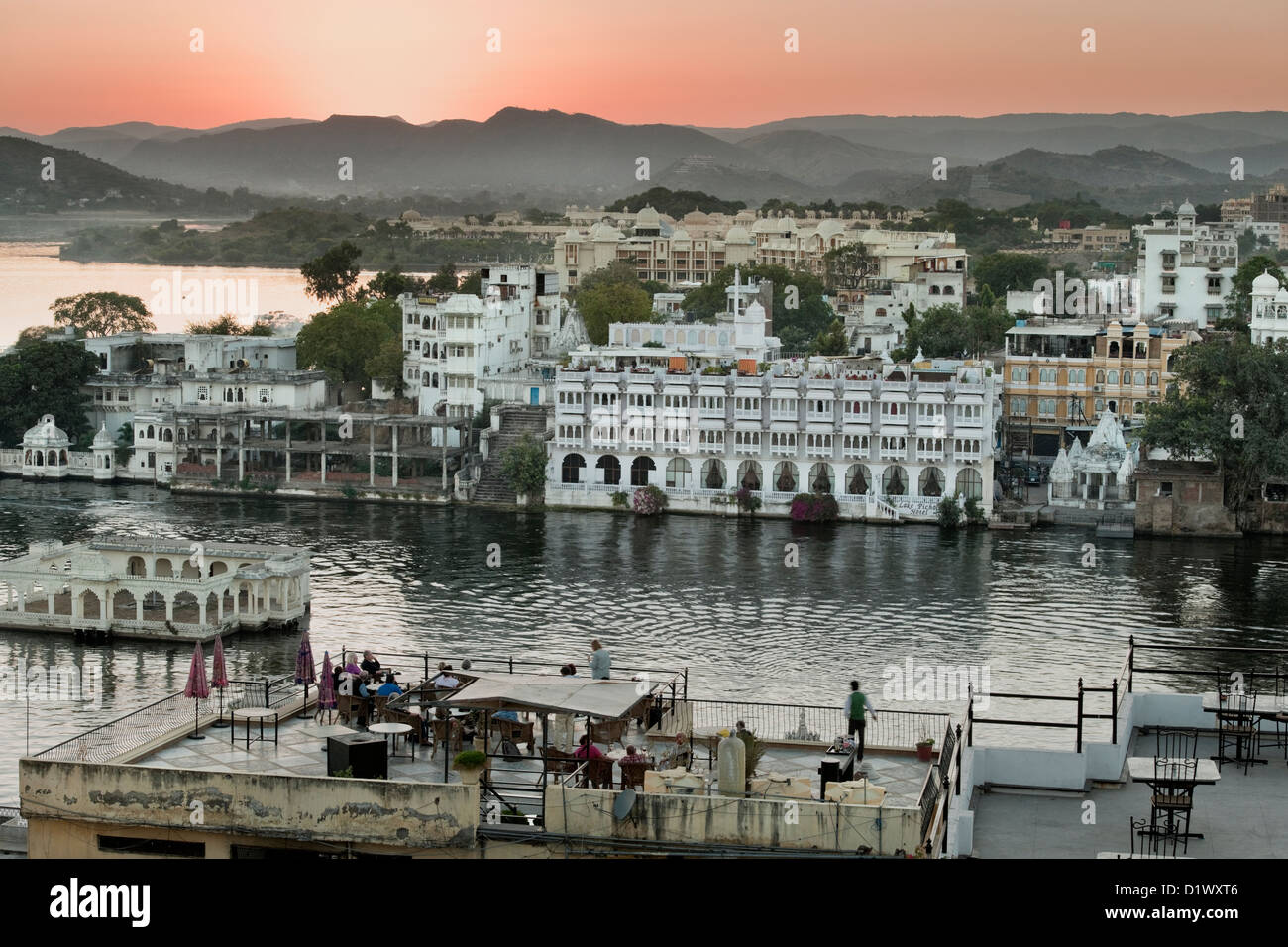 Tramonto sui tetti in Udaipur Rajasthan in India con turisti raccolti sul tetto per guardare la vista. Foto Stock