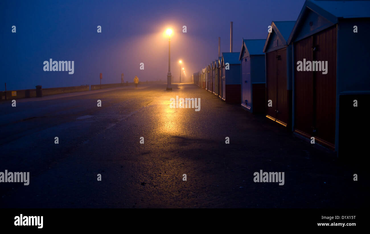 Spiaggia di capanne, notte, lampioni, Brighton e Hove,distante la figura, Strada bagnata Foto Stock