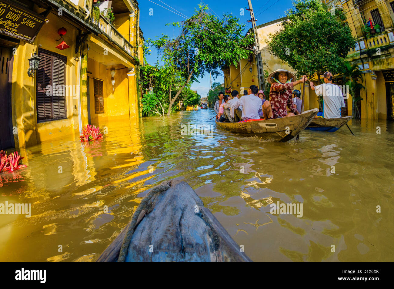 La gente del posto i viaggi attraverso le strade allagate dalla barca, Hoi An, Vietnam Foto Stock