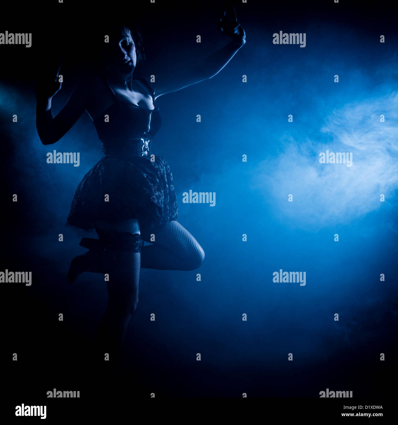 Una giovane donna ballerina dancing in blu acceso il fumo smokey studio Foto Stock