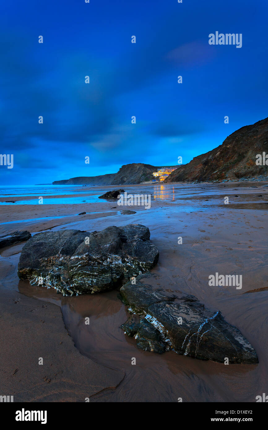 Crepuscolo Tregurrian sulla spiaggia a Watergate Bay Cornwall Inghilterra con le luci dall'hotel e ristoranti riflessa Foto Stock