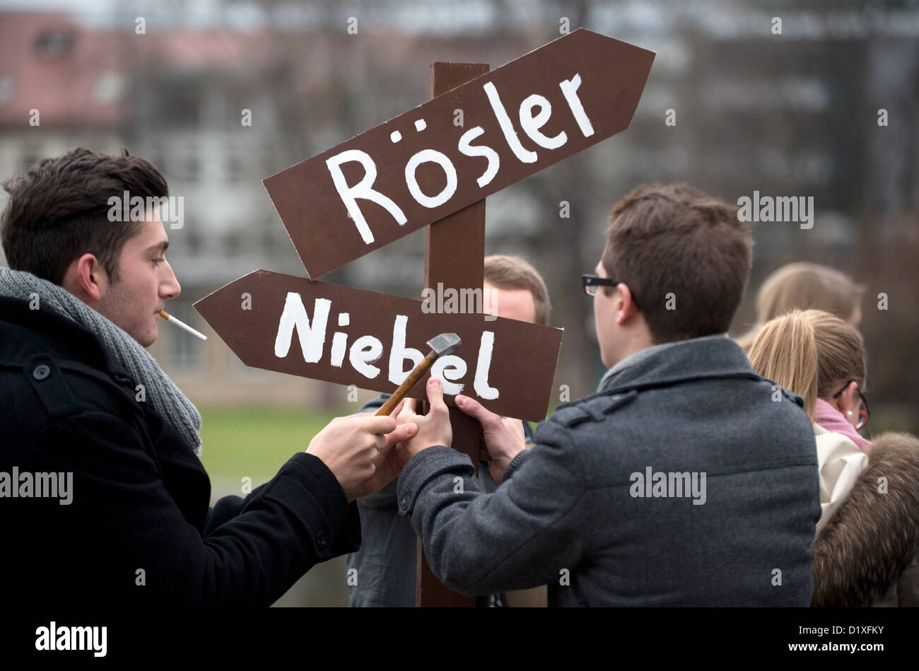 Membri della FDP giovanile dell organizzazione, Julis, mettere un segno posto rivolte in direzioni oppoising con i nomi del Ministro tedesco per la cooperazione e lo sviluppo economico, Dirk Niebel, Presidente della FDP, Philipp Roesler, durante l'Epifania annuale conferenza di partito della FDP a Stoccarda, Germania, 6 gennaio 2013. Foto: Marijan Murat Foto Stock
