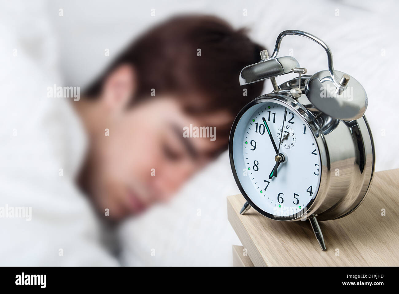 In prossimità di un vecchio orologio sveglia, giovane uomo addormentato Foto Stock