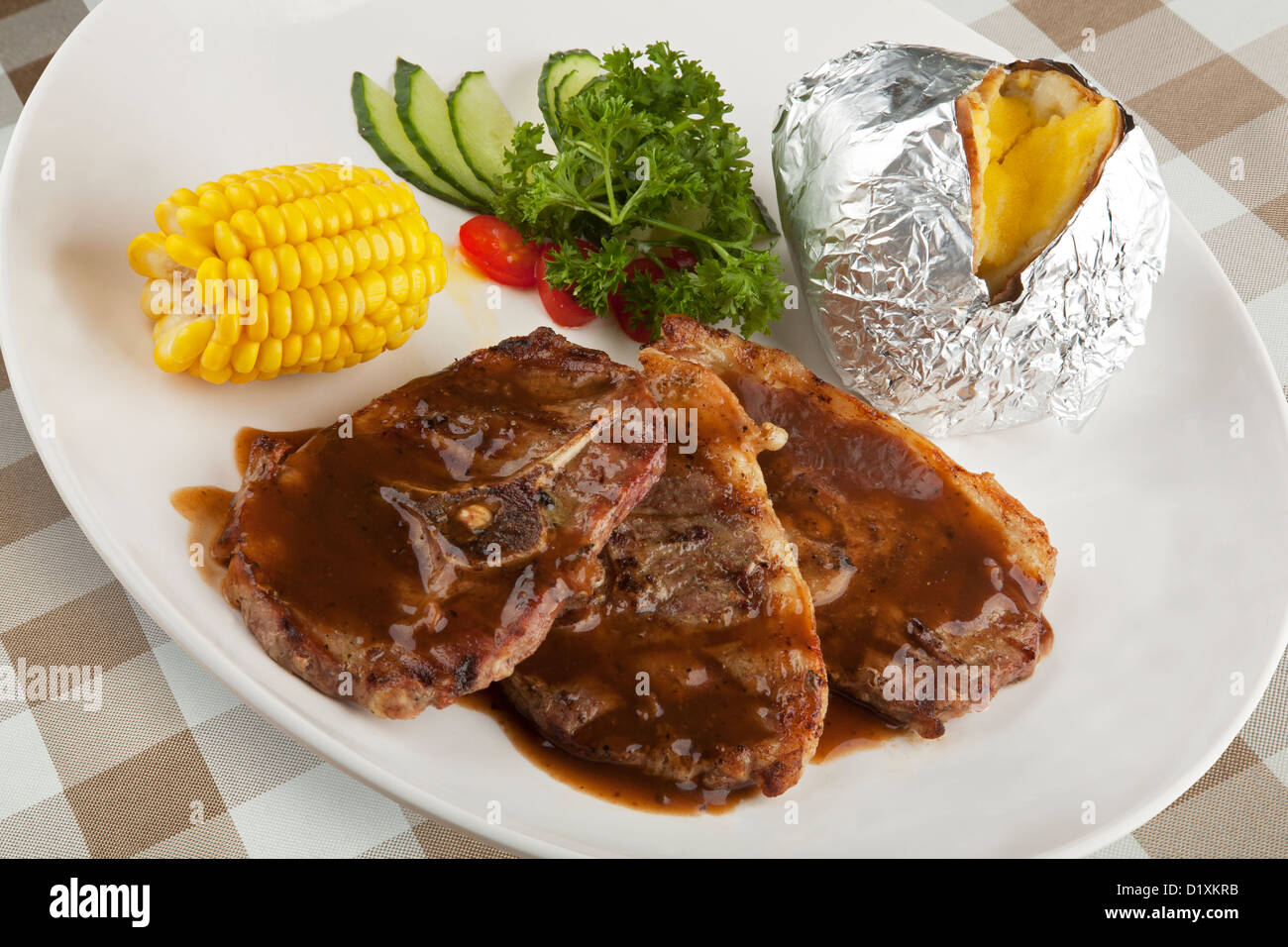 Osso in agnello con salsa gravy e il mais e patate al forno Foto Stock