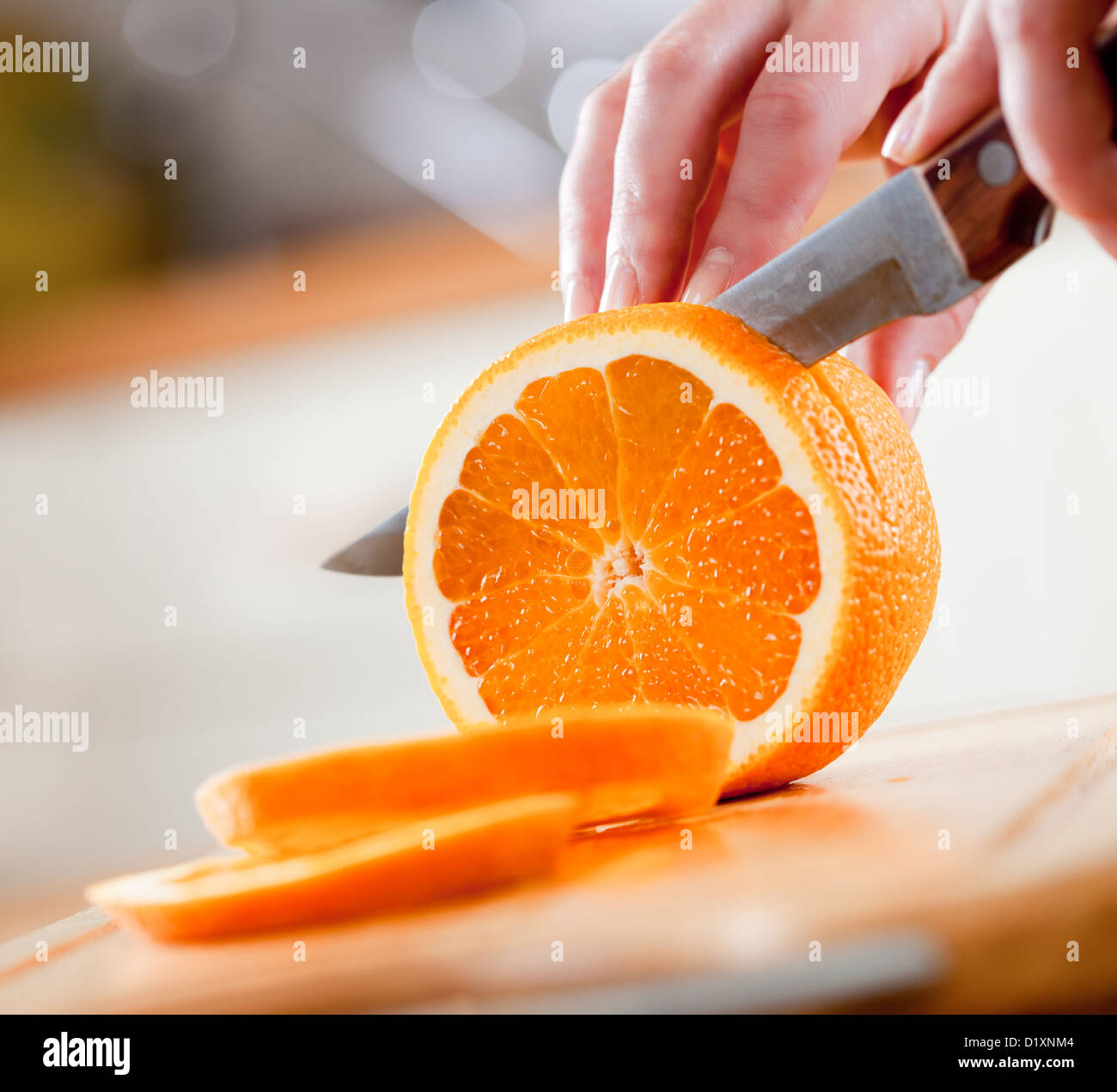 Donna con le mani in mano il taglio di arancia fresca su cucina Foto Stock
