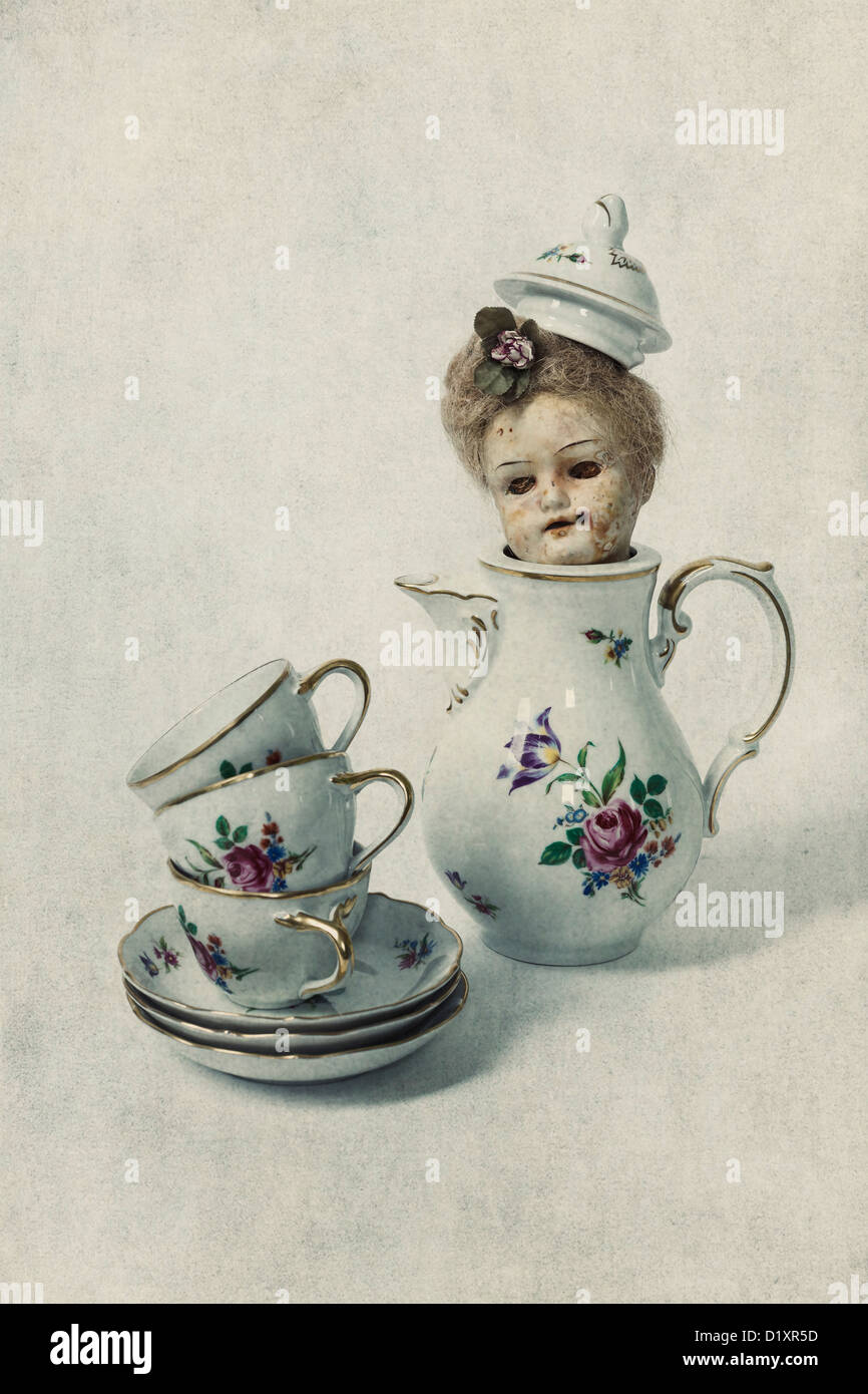 Tre tazze di vintage e di un set per la preparazione di tè pentola con la testa di una vecchia bambola vittoriana Foto Stock