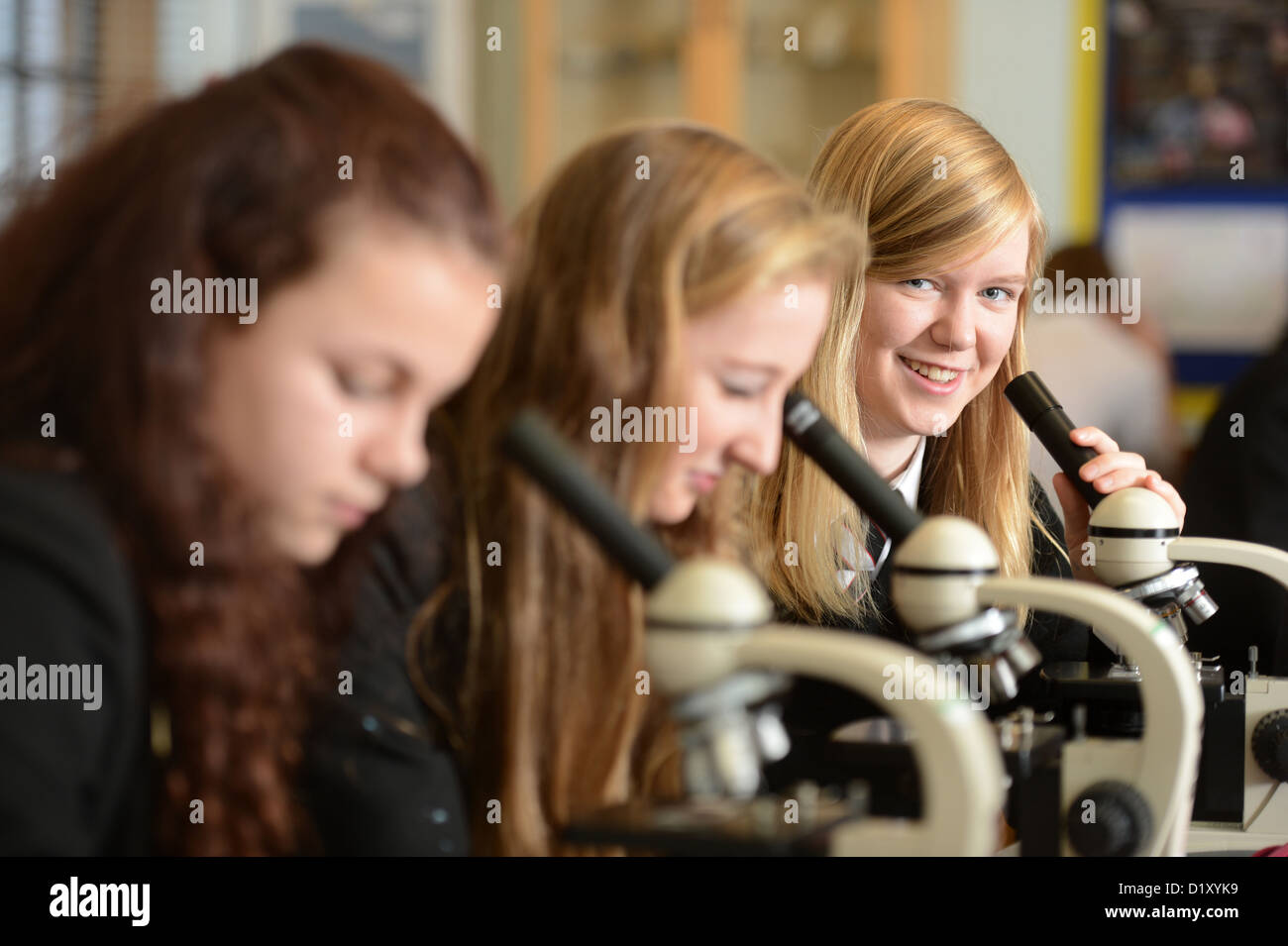 Le ragazze della scuola utilizzando microscopi durante una lezione di scienze a Pâté Grammar School di Cheltenham, Gloucestershire REGNO UNITO Foto Stock