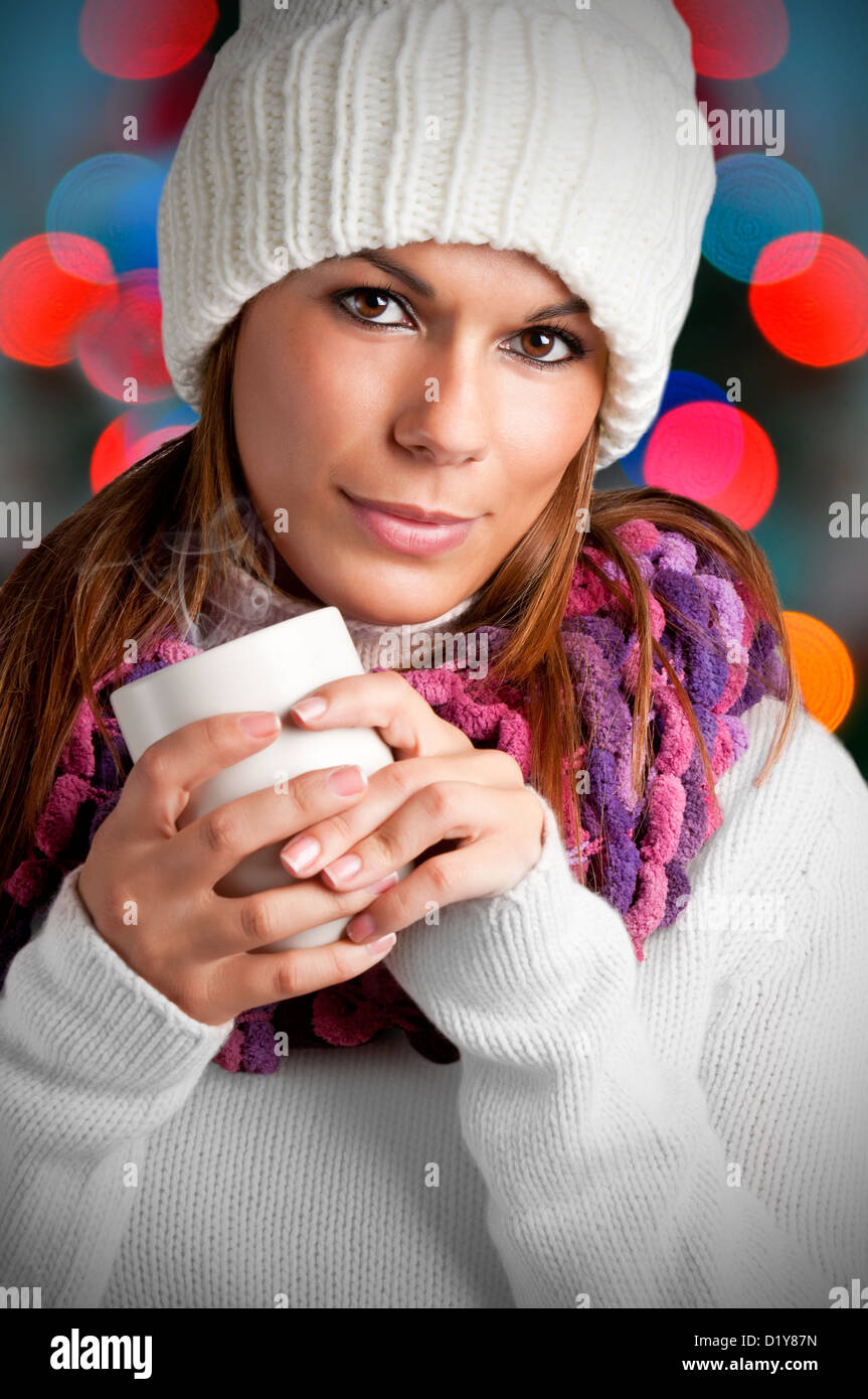 Giovane donna di bere una bevanda calda da una tazza bianca Foto Stock