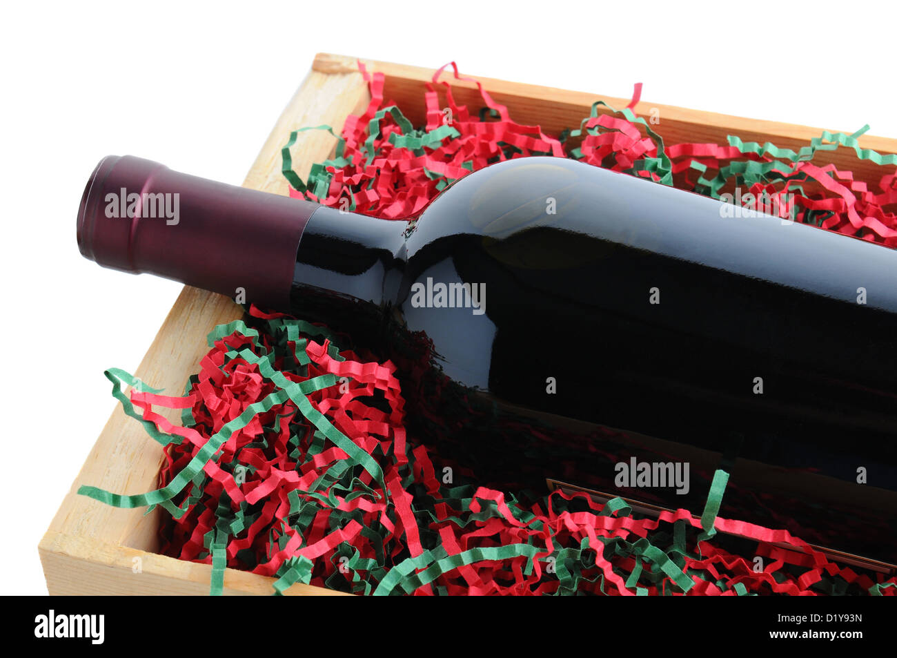 Primo piano di un vino rosso bottiglia in un legno nella cassa di spedizione con shredded carta di riempimento in vacanza di Natale a colori. Foto Stock