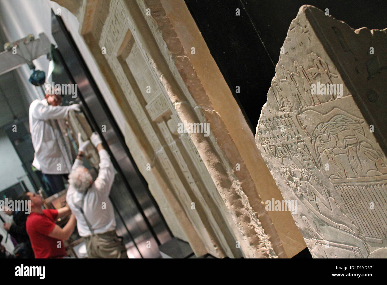 I dipendenti mano un bassorilievo in pietra da 2200 BC su una parete nelle nuove sale del Museo Statale di Arte Egizia a Monaco di Baviera, Germania, 08 gennaio 2013. Il museo si apre a metà del 2013. Foto: Benno Schwinghammer Foto Stock