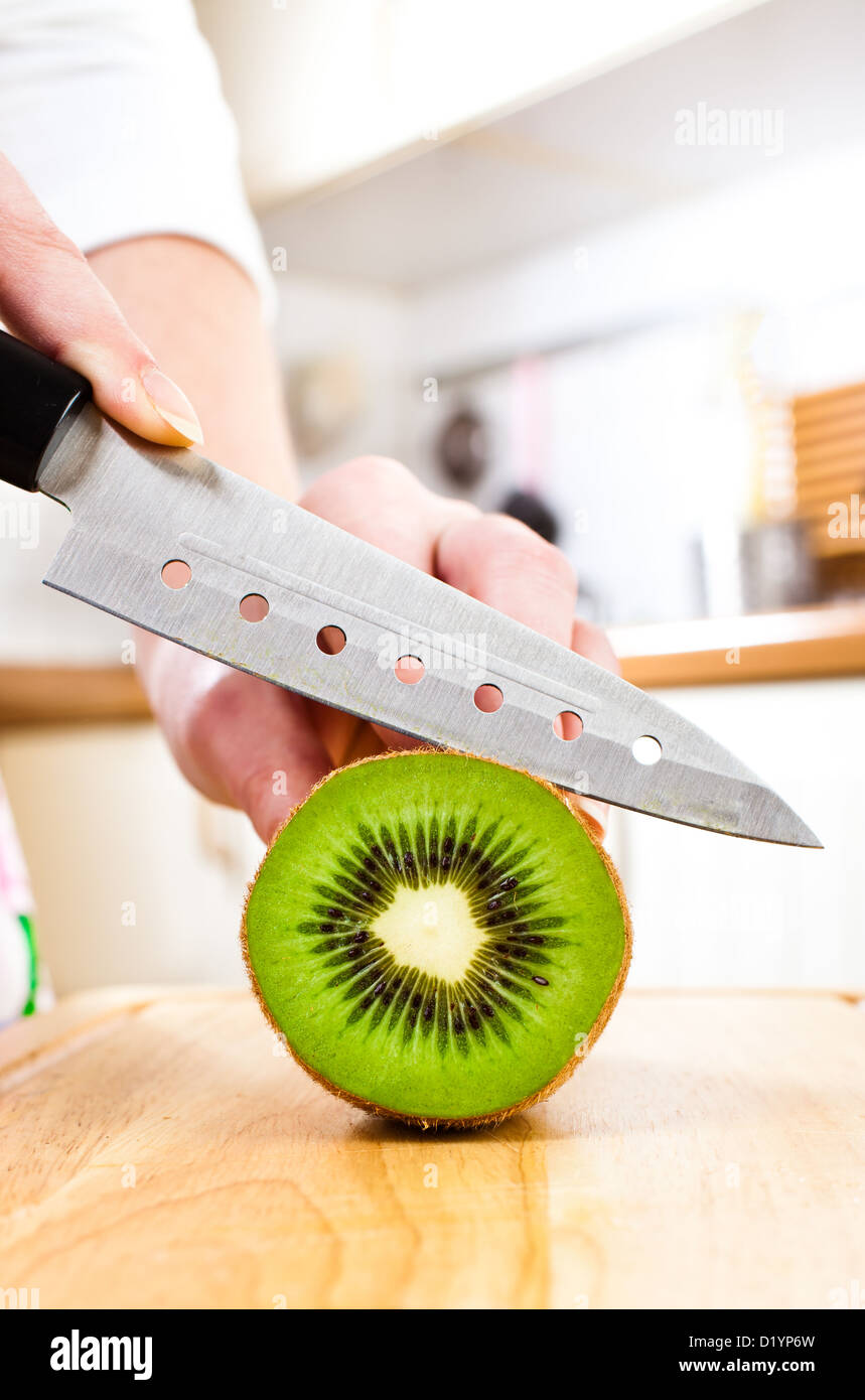 Donna taglio mani fresche Kiwi in cucina Foto Stock
