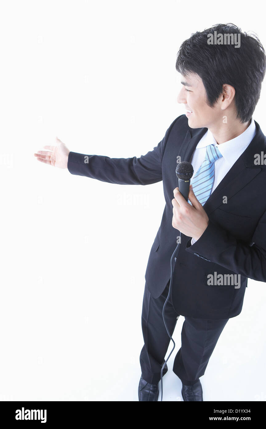 Un imprenditore in un costume nero per spiegare qualcosa utilizzando il microfono Foto Stock
