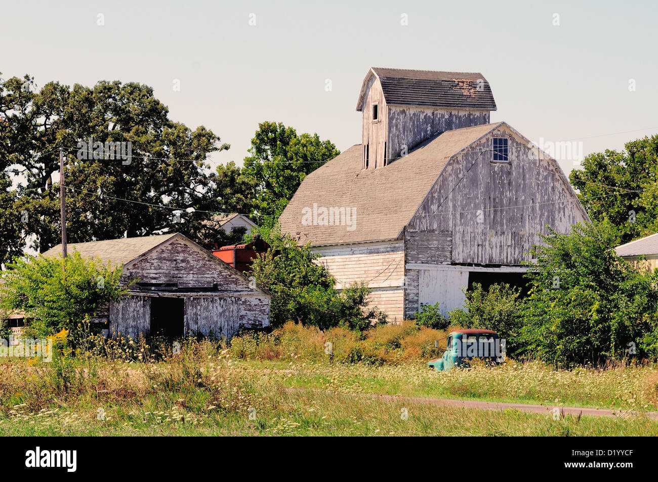 Agricoltura weathered granaio e nella necessità di vernice lungo con un carrello abbandonato Illinois farm. Stati Uniti d'America. Foto Stock
