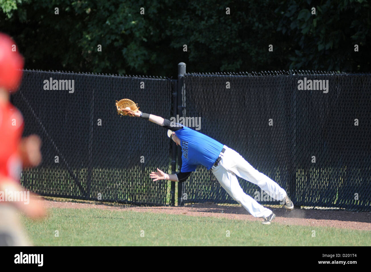 BaseballCatcher estende il suo guanto cattura diving fallo popup durante una scuola di gioco. Foto Stock