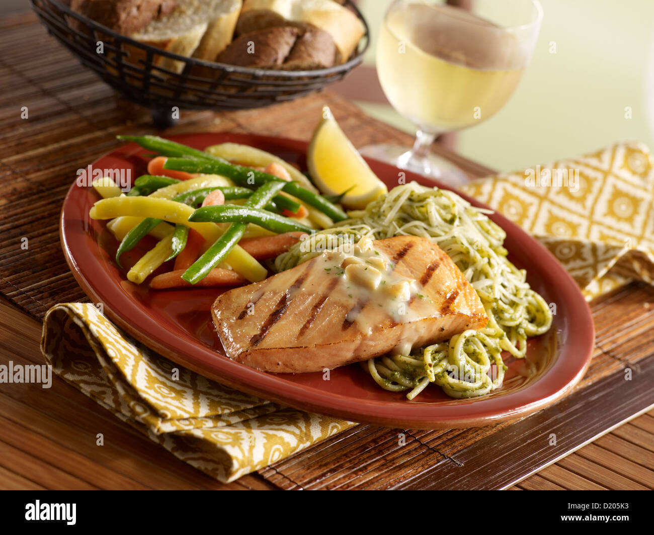 Cena di salmone con aglio arrostito su pesto pasta e servita con verdure medley Foto Stock