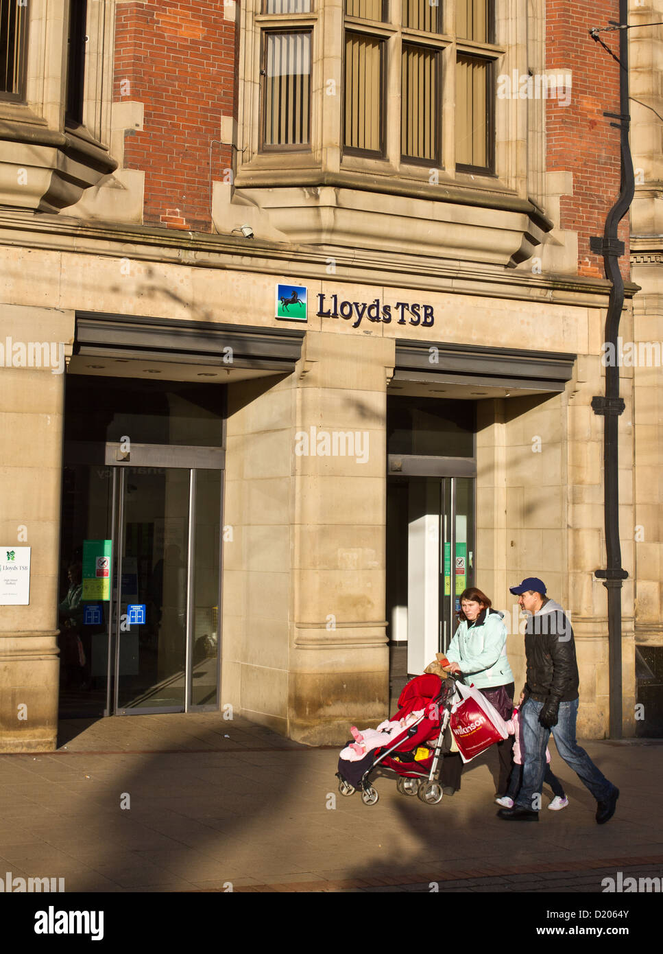 Una giovane coppia con un bambino a piedi passato Lloyds TSB Bank in Church Street nr High Street Sheffield Inghilterra Foto Stock
