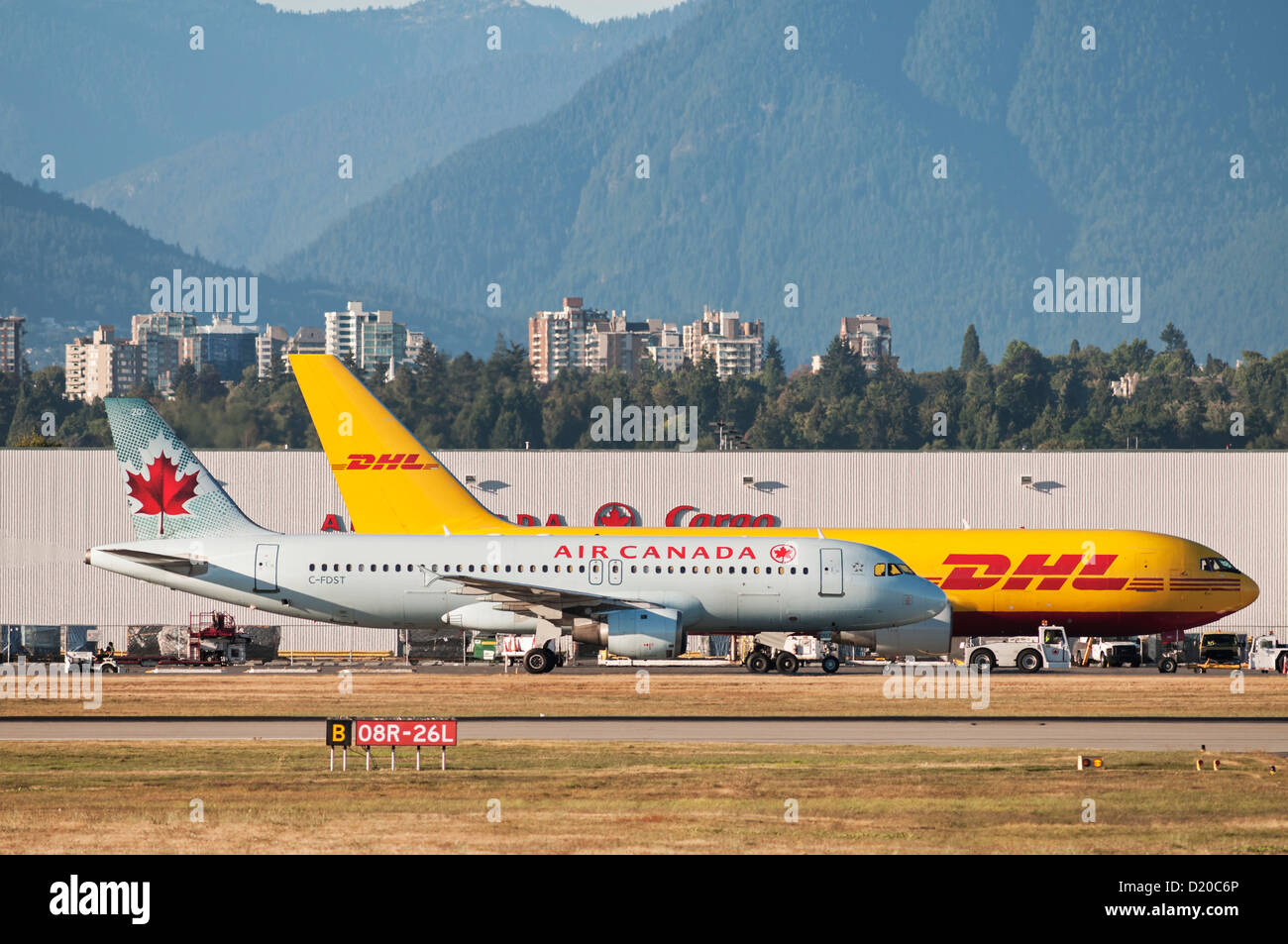 Un Air Canada Airbus A320 jetliner passeggeri taxi passato a DHL Boeing 767 cargo aereo cargo (azionati da aria ABX) Foto Stock