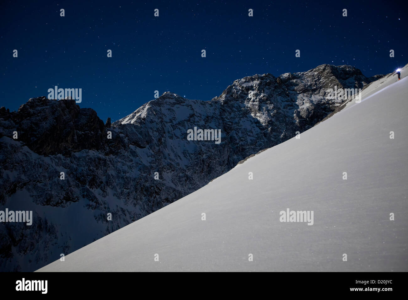 Persona backcountry sci al chiaro di luna con un proiettore, Alpspitz, Wetterstein, Alpi, Baviera, Germania Foto Stock