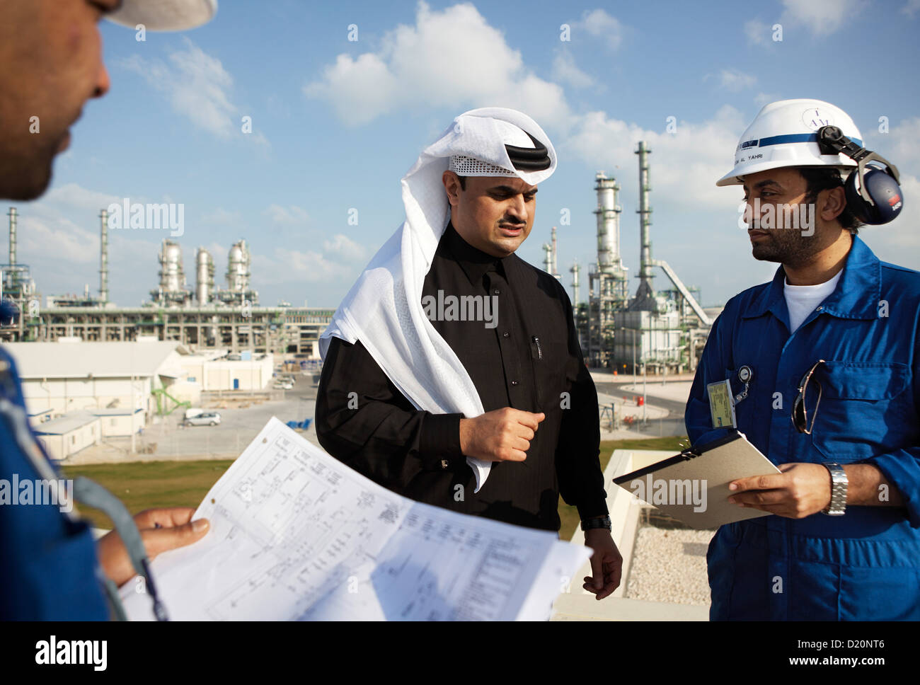 Gli uomini avente un incontro, di raffineria in background, Ras Laffan città industriale, in Qatar Foto Stock