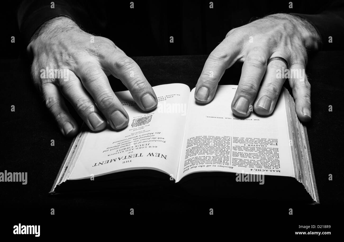 Un uomo la lettura della Sacra Bibbia con due mani Foto Stock