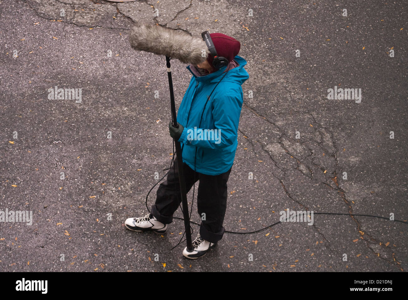 Tecnico Audio cuffie da indossare la registrazione di suoni su strada con un microfono su un polo del braccio con una pelliccia coperchio del parabrezza Foto Stock