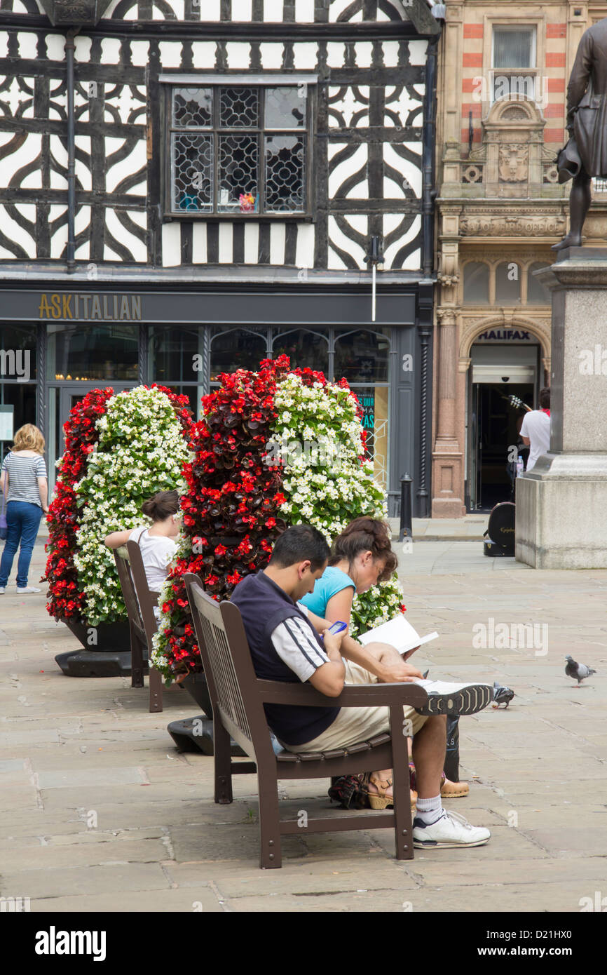 I giovani adulti leggere e rilassarsi nella piazza di Shrewsbury. Foto Stock