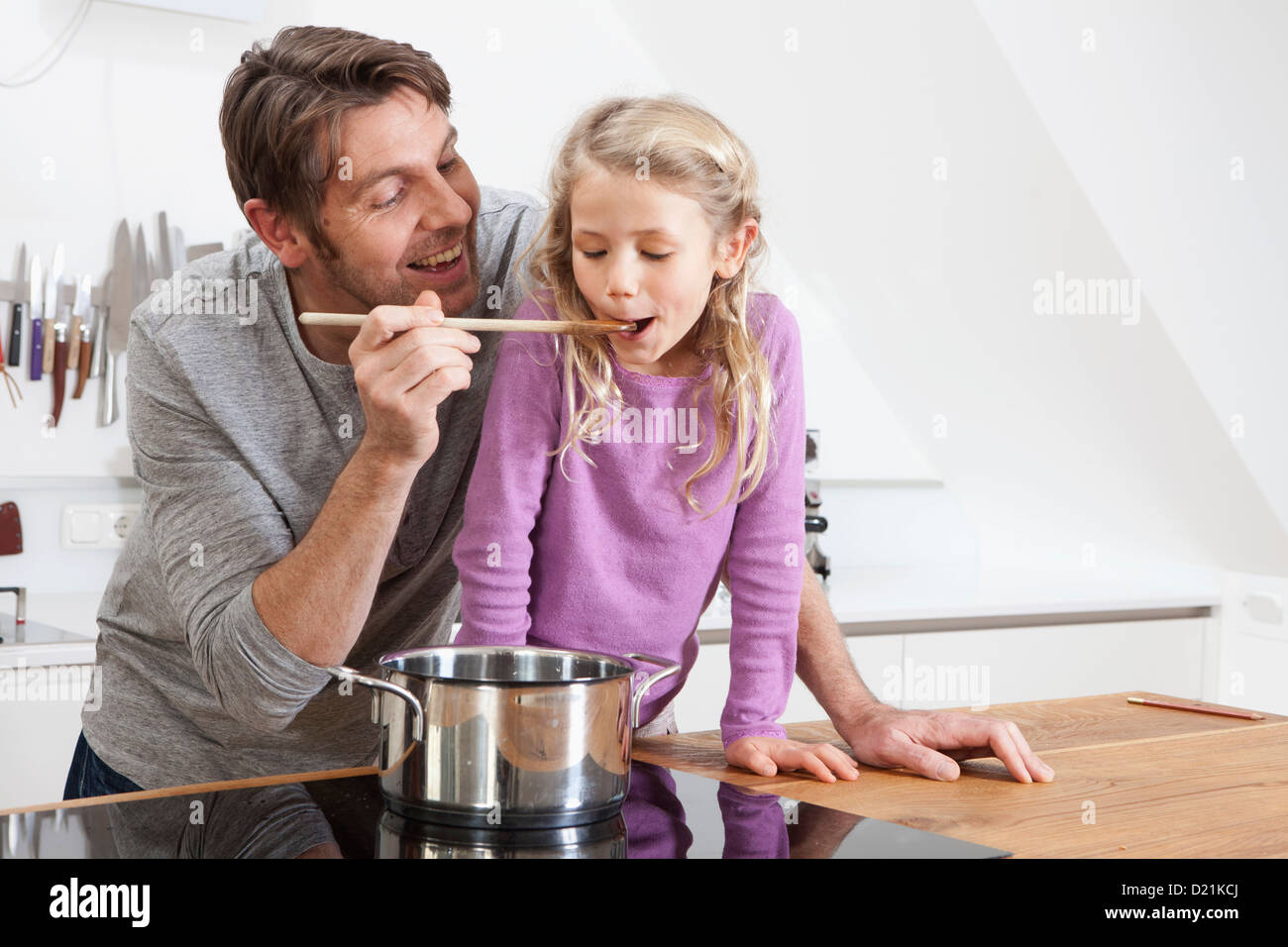 In Germania, in Baviera, Monaco di Baviera, padre figlia di alimentazione in cucina, sorridente Foto Stock