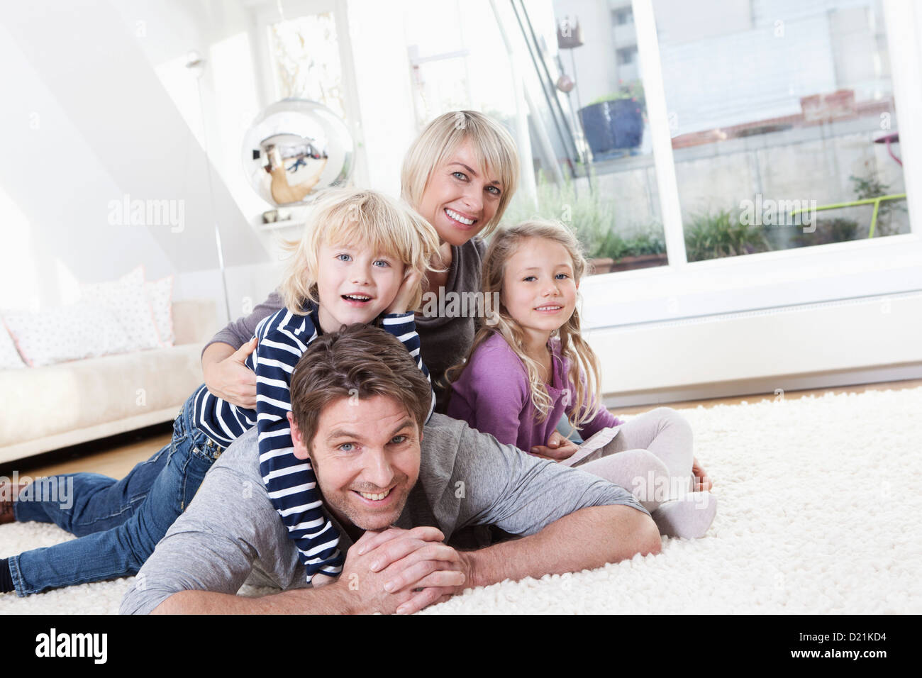 In Germania, in Baviera, Monaco di Baviera, Famiglia giacente sul piano, ritratto, sorridente Foto Stock
