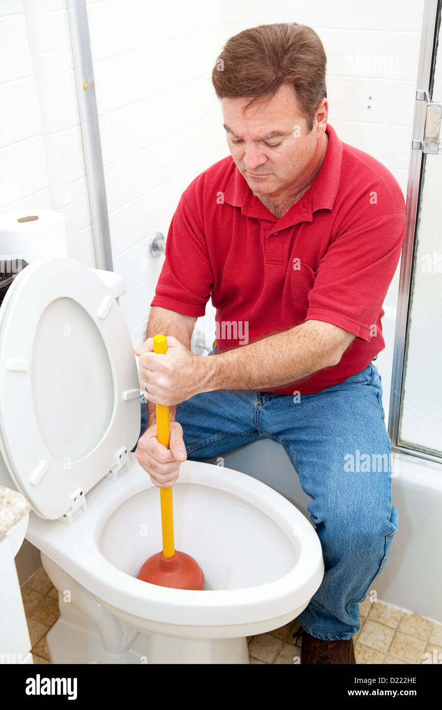 Uomo che utilizza uno stantuffo per pulire il wc Foto stock - Alamy