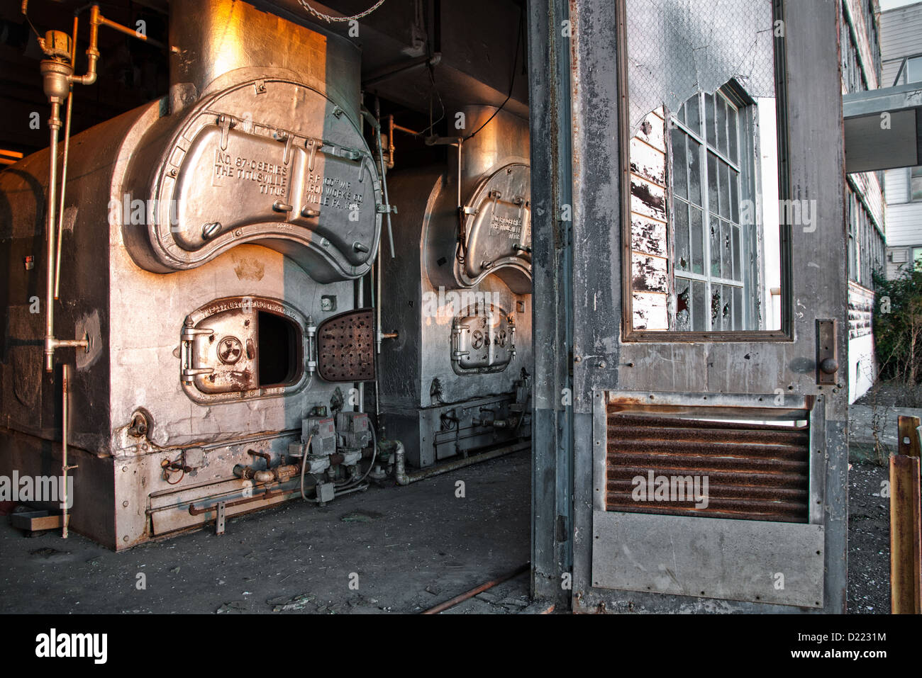 Aprire la porta conduce alla caldaia vintage in mezzo alle finestre rotte al mare isola cantiere navale. Foto Stock