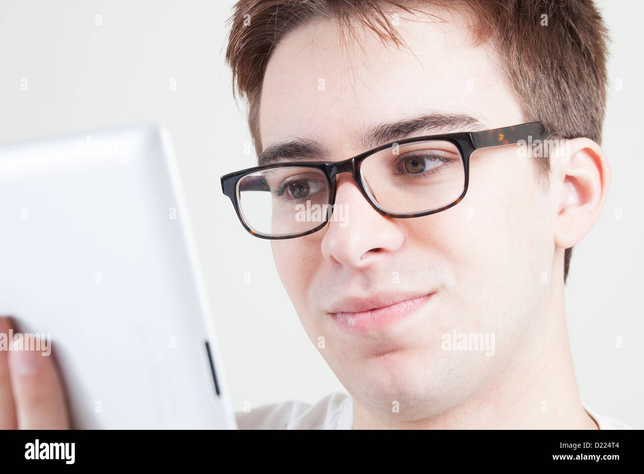 Giovane maschio che indossano occhiali guardando lo schermo del suo computer portatile o digitale compressa. Close up. Foto Stock