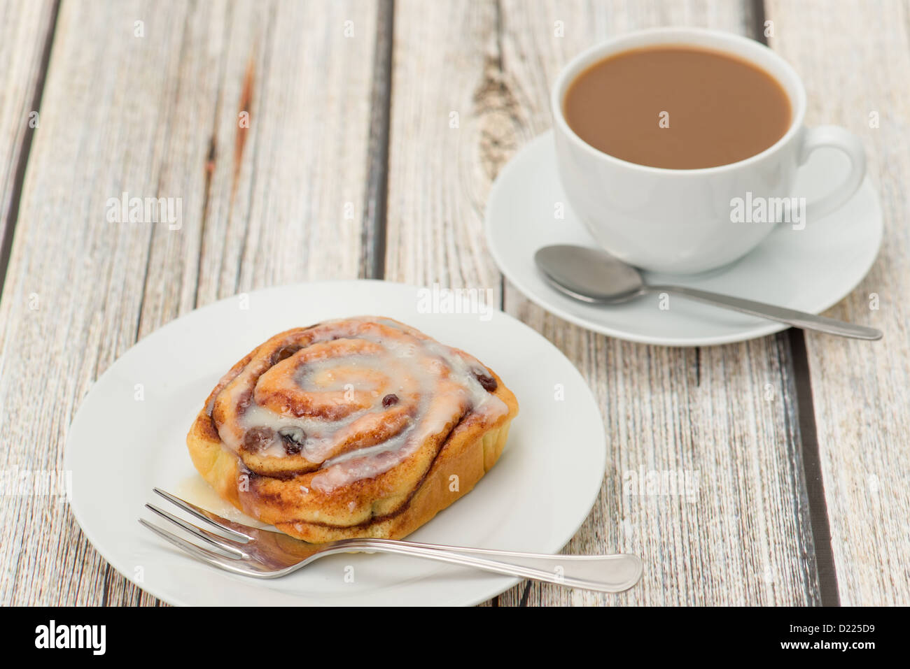 Deliziosa cannella bun servita su una piastra bianca con una tazza di caffè bianco - studio shot Foto Stock