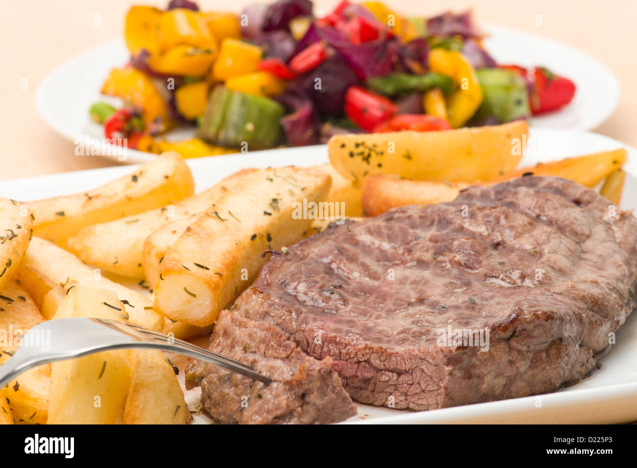 Scamone bistecca e chunky herb fries la cena con un lato piatto di arrosto di verdure miste - studio shot Foto Stock