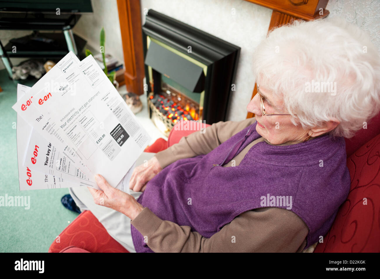 Una vecchia donna che mantiene le bollette di energia Foto Stock