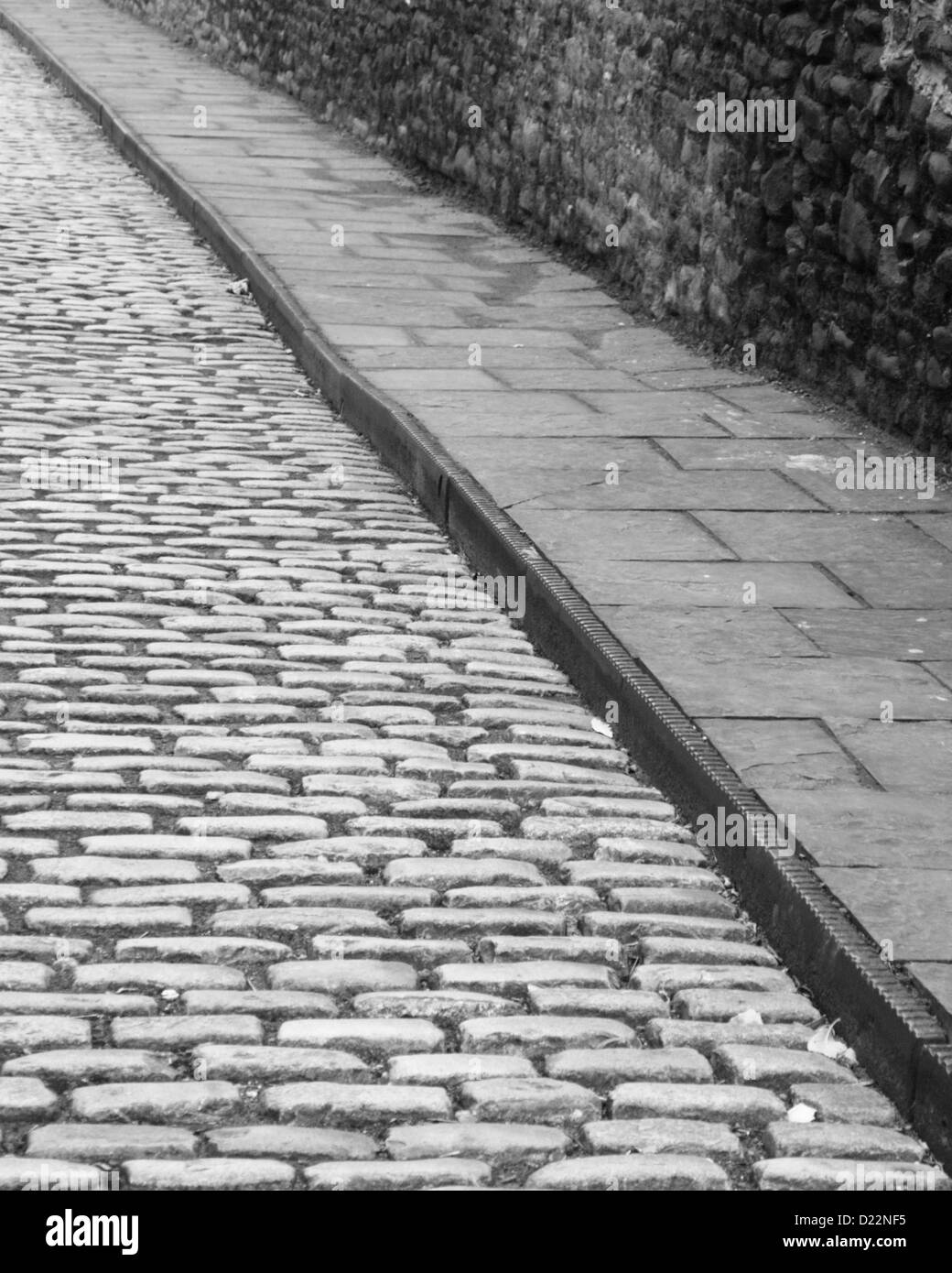 Strada di ciottoli con cordolo di ferro in una vecchia strada dietro il porto di Bristol, Bristol. Cordoli di ferro protetto il marciapiede dal ferro delle ruote del carrello Foto Stock