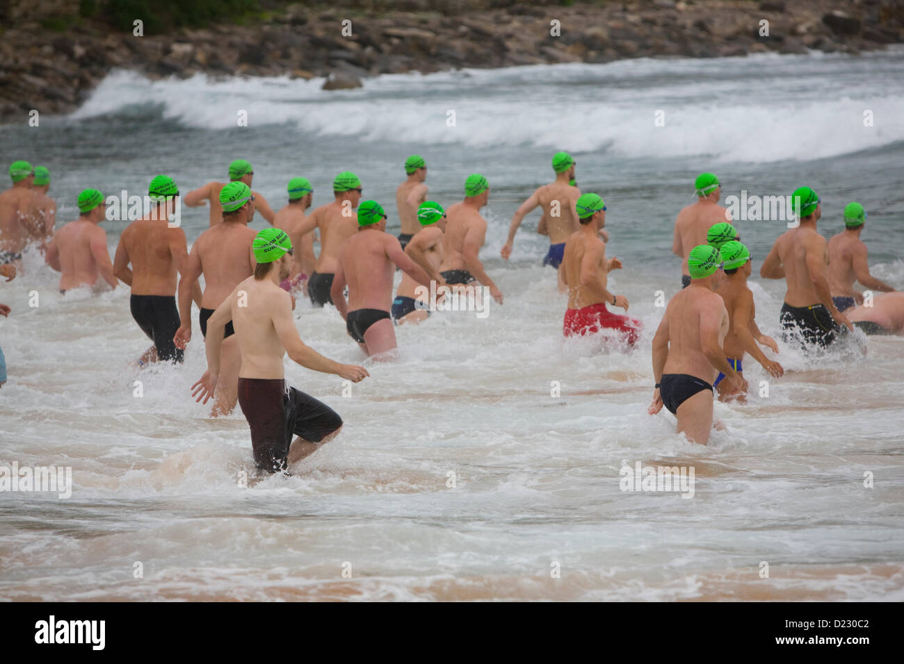 Sydney, Australia. 13th Jan, 2013. L'Avalon Beach 1,5km Ocean Swim Race, parte della serie di eventi pittwater Ocean Swim, Avalon Beach, Sydney, NSW, Australia, mentre i concorrenti di Swim Race corrono nell'oceano surf indossando berretti verdi da nuoto Foto Stock