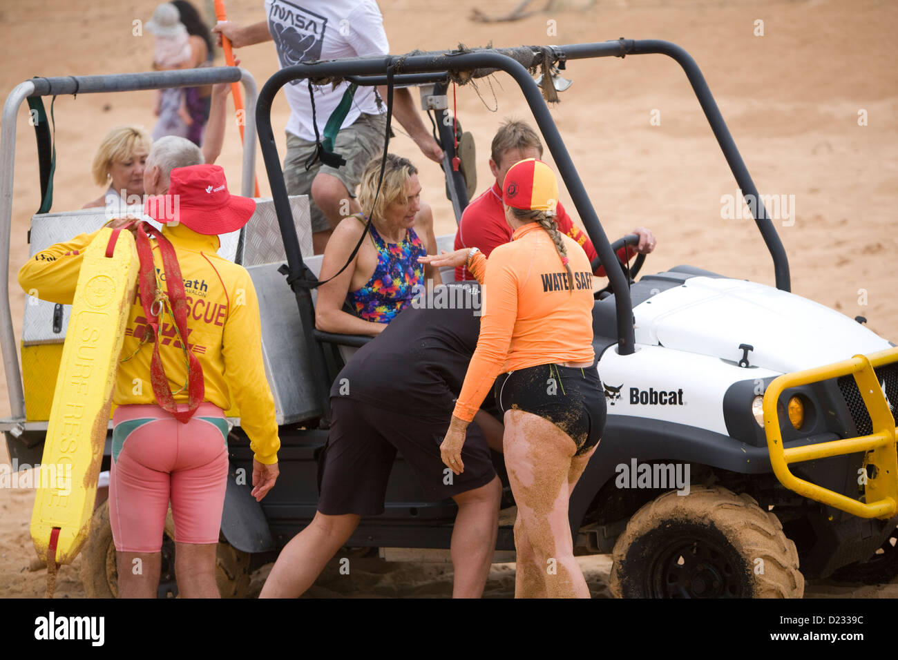 Navigare il personale di soccorso aiutare un ferito signora su una spiaggia di Sydney, Australia Foto Stock