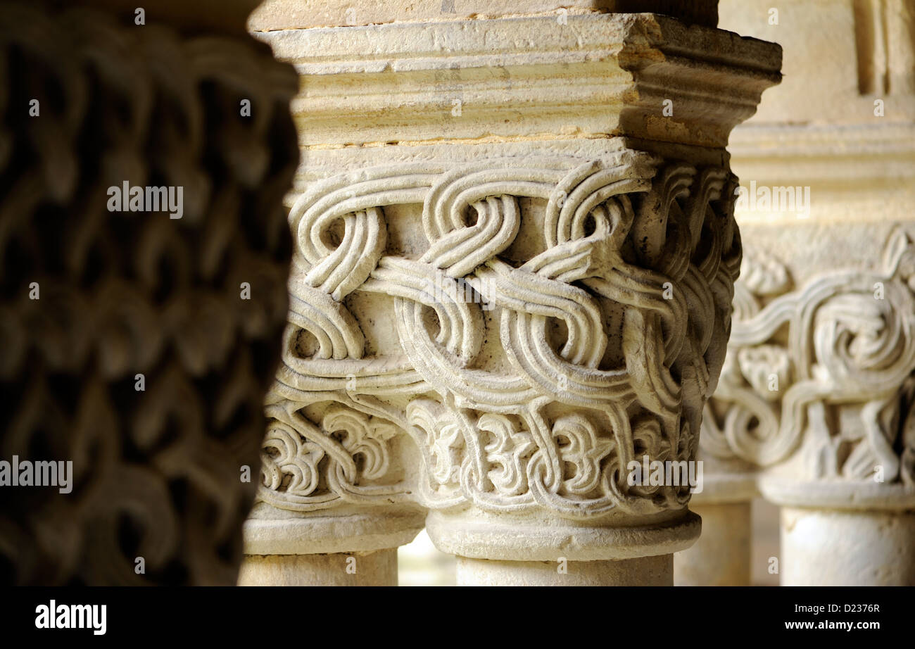 Intracately capitelli scolpiti su colonne che sorreggono archi che formano il colonnato del romanico Colegiata Santillana del Mar Foto Stock