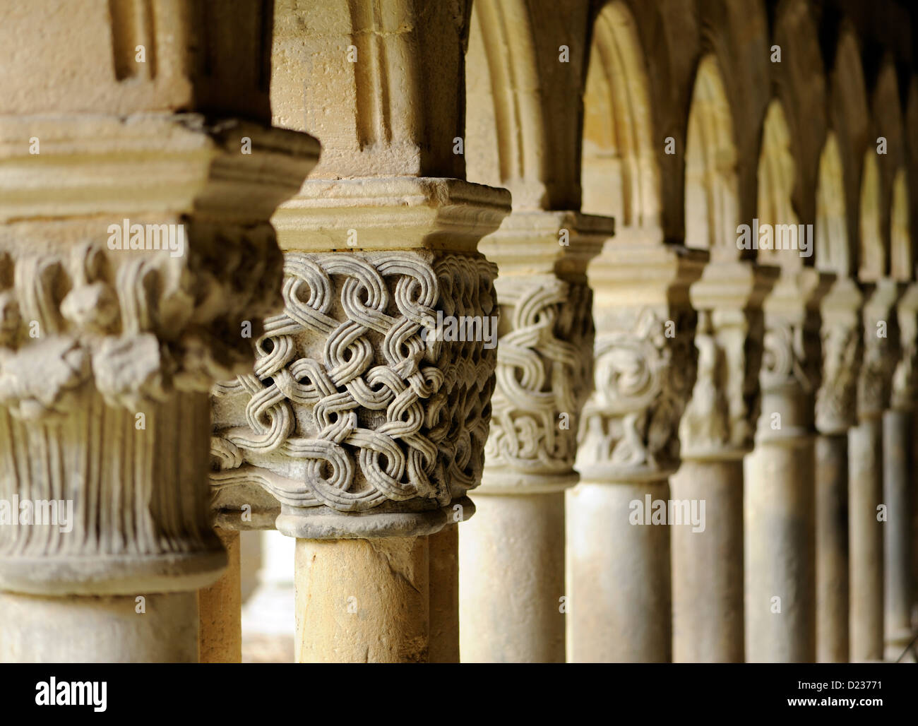 Intracately capitelli scolpiti su colonne che sorreggono archi che formano il colonnato del romanico Colegiata Santillana del Mar Foto Stock