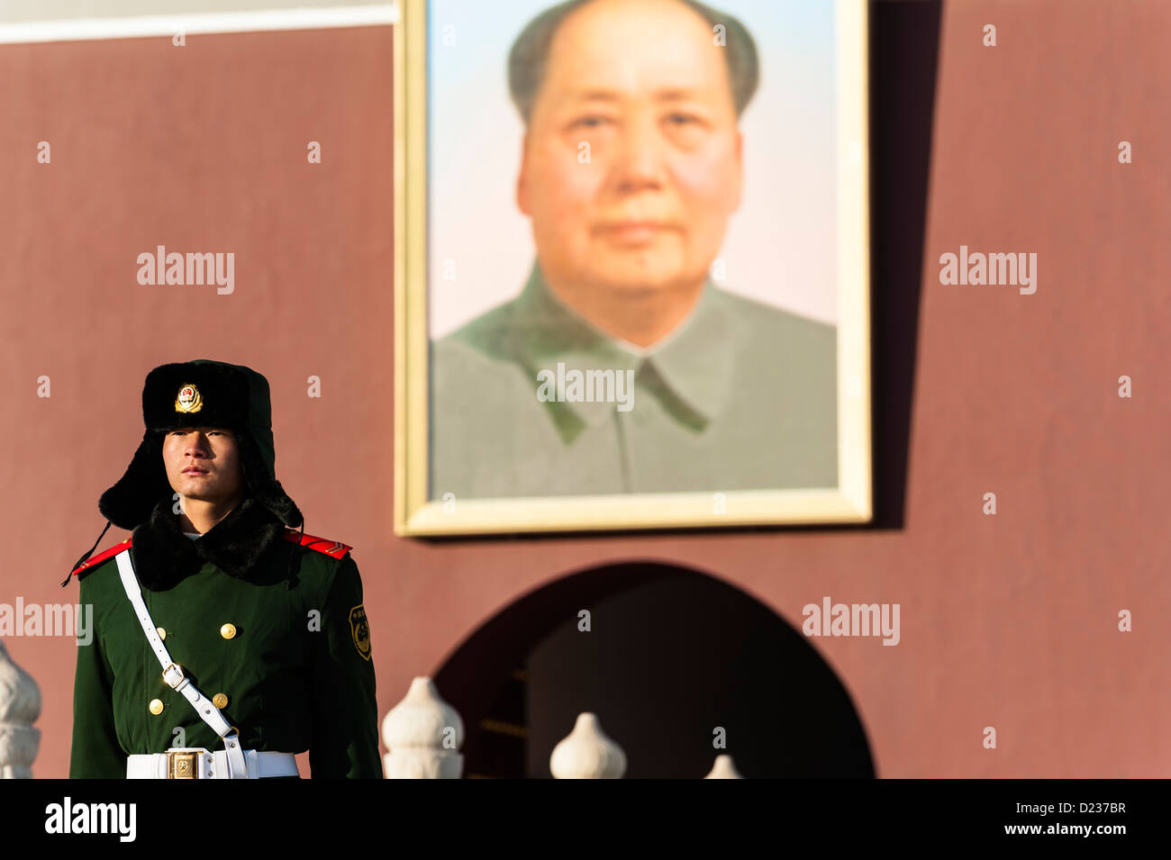 Un poliziotto in piedi di fronte a foto di Mao Zedong Foto Stock